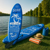 Inflatable paddle board on lakeside shore with summer sun, blue water, and adventure gear arranged nearby