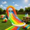Vibrant inflatable water slide in a sunny backyard with beach balls, towels, and eco-friendly cleaning supplies on grass