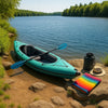 Modern inflatable kayak docked by sparkling blue lake with gear, greenery, and bright sun